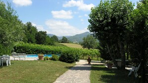 A stone pathway leading to a pool area with outdoor seating and lush greenery. - Vacation Home in Pilarciano with 4 bedrooms sleeps 7 (Pilarciano)