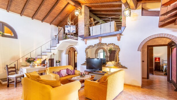 A spacious living room with a high ceiling, a staircase leading to an upper level, and a large mirror with an ornate frame. - Vacation Home in Pilarciano with 4 bedrooms sleeps 7 (Pilarciano)