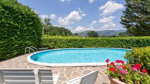 A swimming pool with stone tiles, surrounded by greenery and a view of mountains. - Vacation Home in Pilarciano with 4 bedrooms sleeps 7 (Pilarciano)