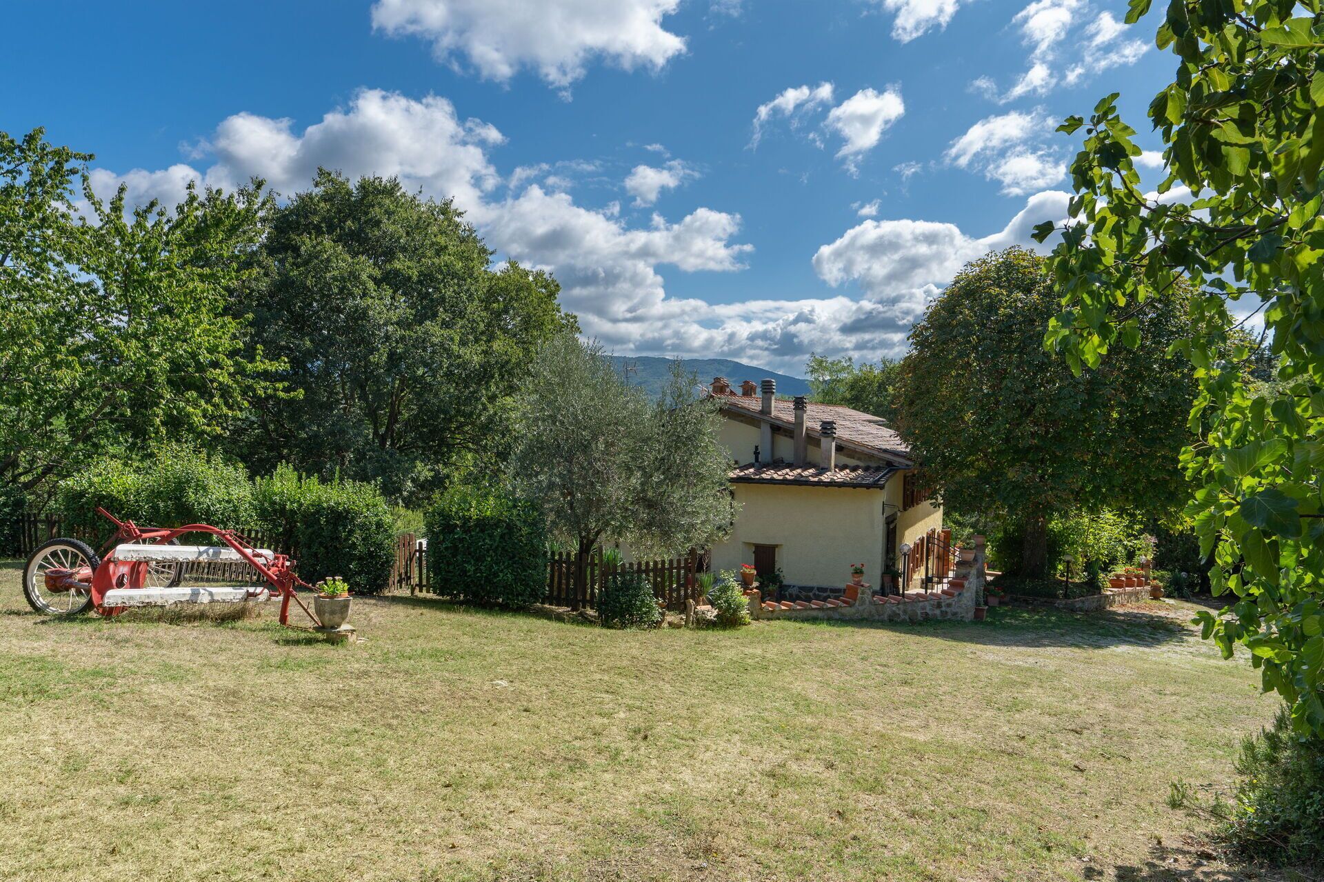Ein Haus mit Ziegeldach, umgeben von einem gepflegten Rasen und Bäumen.
