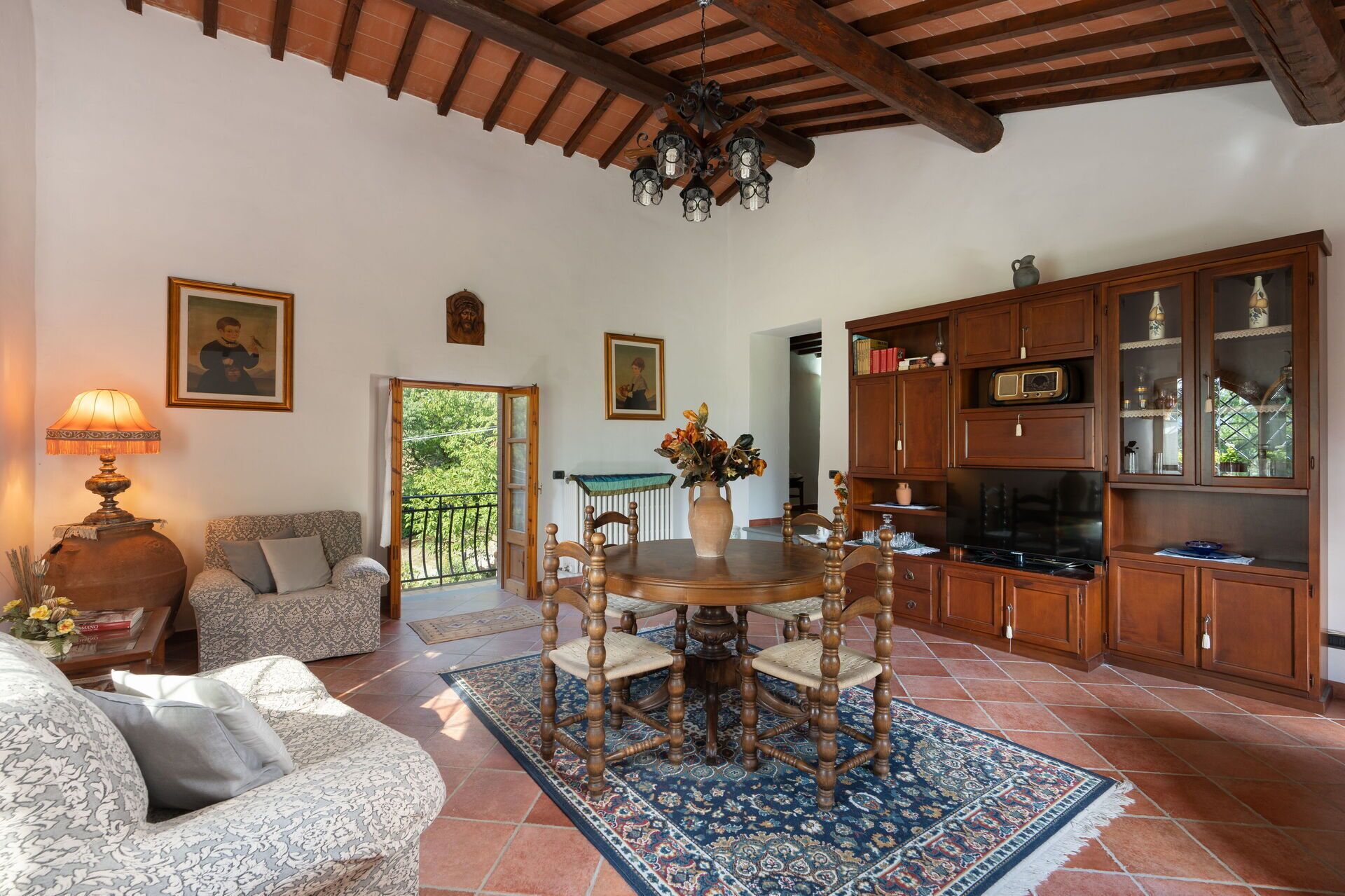 Una sala de estar acogedora con una mesa de comedor de madera, sofás estampados y una alfombra grande.