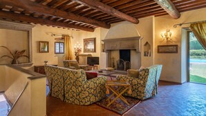 A cozy living room with a fireplace, patterned sofas, and a wooden ceiling.