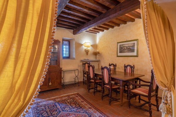 Une salle à manger avec une table et des chaises en bois, un tapis à motifs et une fenêtre donnant sur un beau paysage.