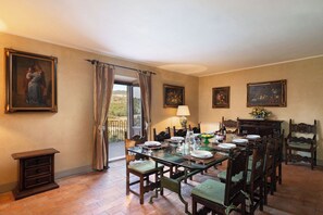 A dining room with a glass table, wooden chairs, and a view through a large window.