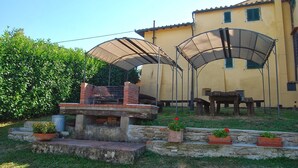 Un área de patio con chimenea de ladrillo, asientos exteriores y plantas en macetas.