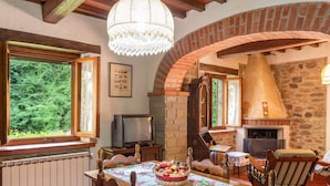 Un coin repas rustique avec une cheminée en briques, des meubles en bois et un lustre.