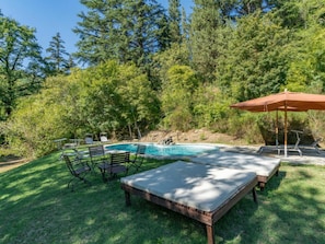 Un giardino con piscina, un pontile in legno e mobili da esterno.