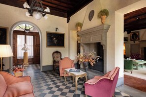 Una habitación con piso a cuadros, chimenea y candelabro.
