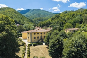 Un edificio giallo con giardino e vista sulle colline verdi.