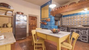Une cuisine avec une table et des chaises en bois, un réfrigérateur et un plan de travail bleu recouvert de carreaux.
