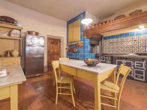 Una cucina con tavolo e sedie in legno, un frigorifero e uno schienale piastrellato di blu.