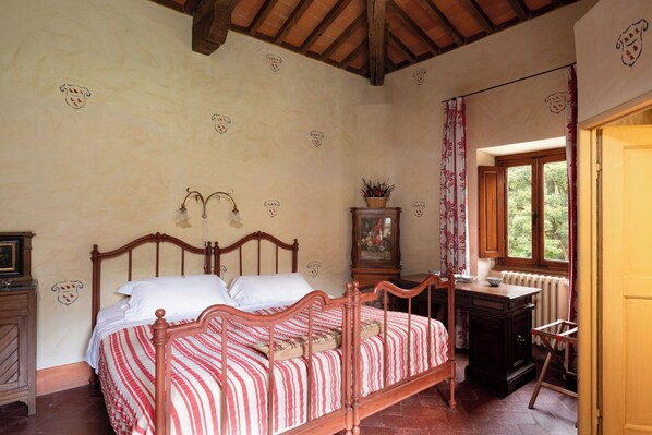 Un dormitorio con cama de madera, un radiador, una ventana con cortinas y un armario de madera.