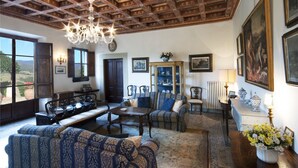 Amplia sala de estar con techo de madera alto, un candelabro y vistas al exterior.