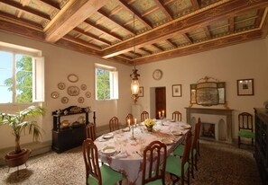Enjoy a traditional dining experience with fine china, glassware, and a beautiful centerpiece, surrounded by elegant furnishings and a warm fireplace.