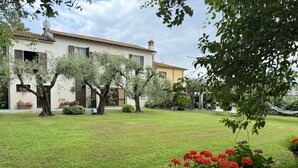A well-maintained garden with a lawn, potted plants, and a building with a tiled roof.