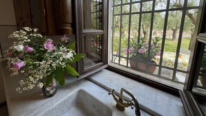 A bathroom with a marble sink, a vintage faucet, and a window with a metal grid.