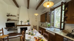 A kitchen with wooden cabinets, a dining table set for four, a TV, and a window with a view of greenery.