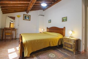 Ein Schlafzimmer mit einem hölzernen Bett, Nachttischlampen, einem kleinen Holzschrank und einem gemusterten Teppich.