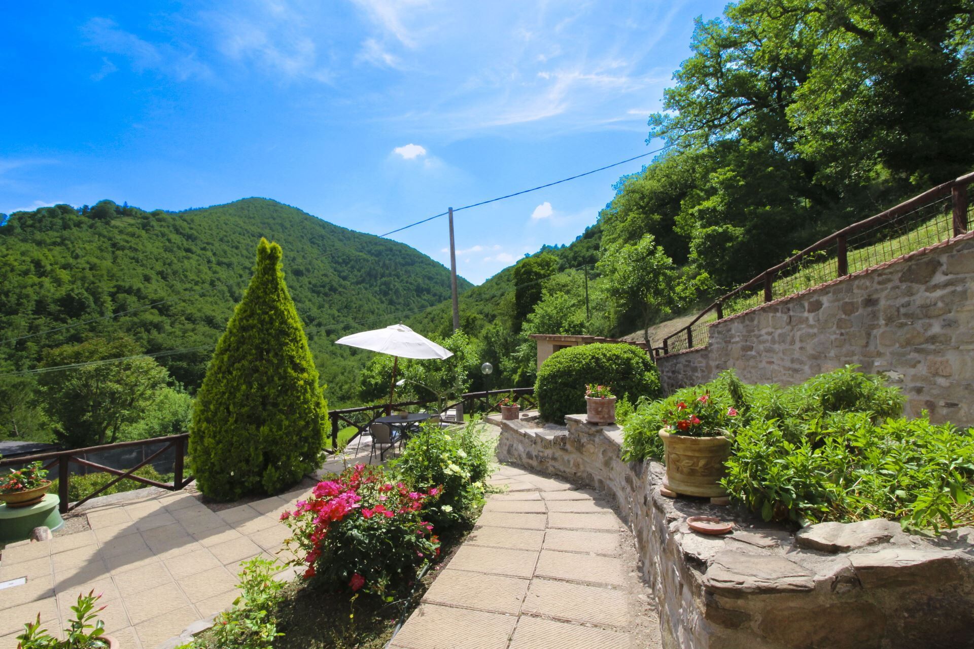 Une terrasse avec des marches en pierre, des plantes en pot et une table avec des chaises.
