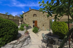 A stone building with a wooden door, a staircase, and a patio area with outdoor seating.