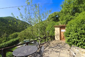 A rustic outdoor seating area with a table and chairs, a wooden fence, and a small building with a window.