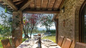 Una mesa lista para comer, con vista a una piscina y árboles.