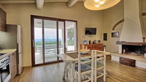Una cocina con una isla grande, un comedor con sillas blancas, una chimenea y un televisor montado en la pared.