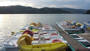 A row of colorful inflatable boats docked at a pier with a calm lake and hills in the background. - Wonderful private villa for 4 guests with WIFI, TV, pets allowed and panoramic view (Porretta Terme)