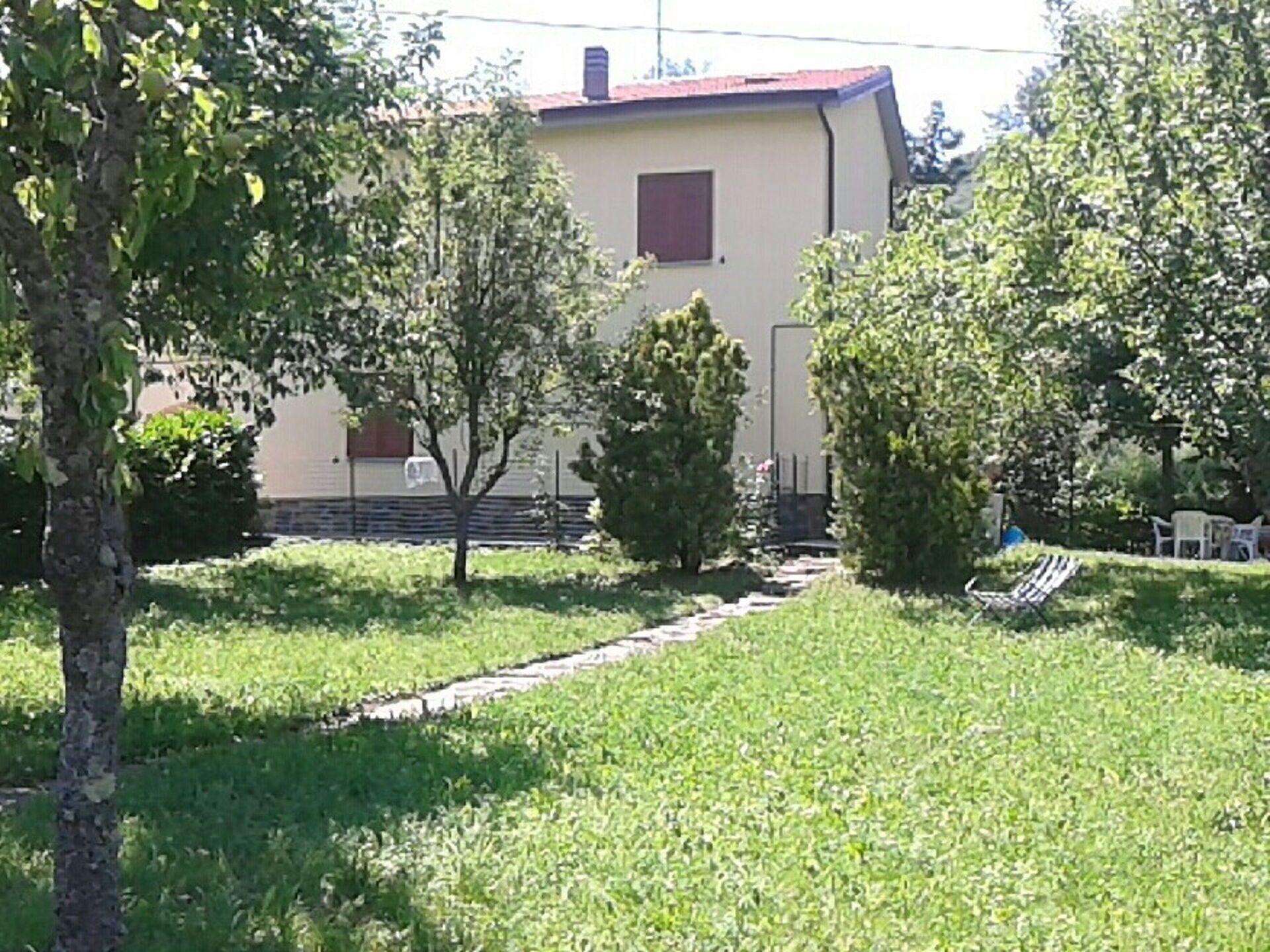 A house with a paved driveway, surrounded by trees and a well-maintained lawn.