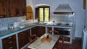 A kitchen with wooden cabinets, a marble countertop, and a window with a view. - Wonderful private villa for 14 people with private pool, WIFI, TV, terrace and panoramic view (La Ginestra)