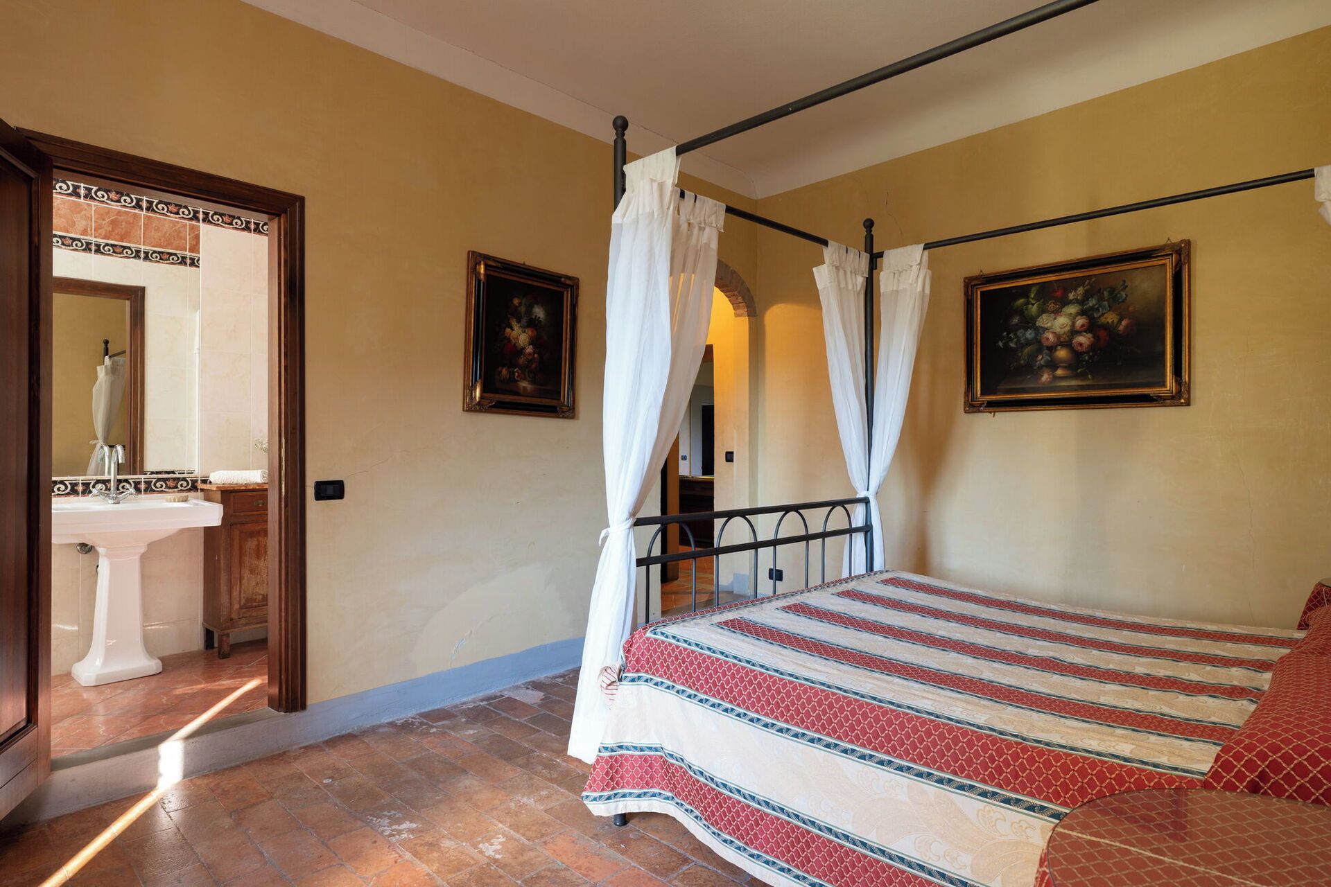 Une chambre à coucher avec un lit, une table de chevet, un miroir et deux tableaux accrochés au mur.