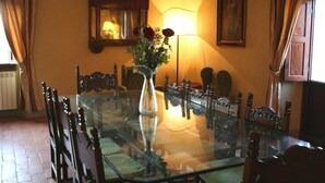 A dining room with a glass table surrounded by wooden chairs, a vase with flowers, and a lamp. - Wonderful private villa for 14 people with private pool, WIFI, TV, terrace and panoramic view (La Ginestra)