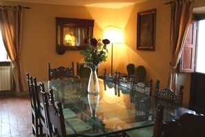 A dining room with a glass table surrounded by wooden chairs, a vase with flowers, and a lamp. - Wonderful private villa for 14 guests with WIFI, private pool, TV, terrace and panoramic view (La Ginestra)