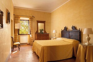 Ein Schlafzimmer mit zwei Betten, einem Schminktisch, einem Stuhl und einem Fenster mit Vorhängen.