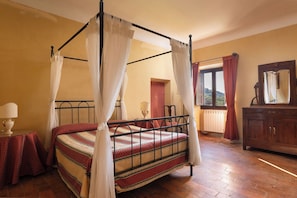 A four-poster bed with a canopy, a wooden dresser, a mirror, and a window with curtains. - Wonderful private villa for 14 people with private pool, WIFI, TV, terrace and panoramic view (La Ginestra)