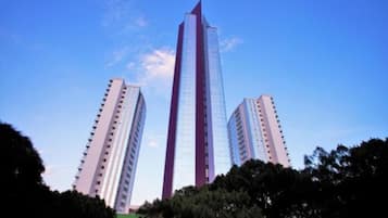 Un rascacielos alto y moderno con fachada de vidrio reflectante y un llamativo esquema de color rojo y blanco.