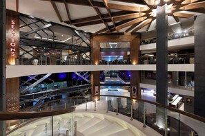 A multi-level shopping mall with glass railings, wooden beams, and a central atrium.
