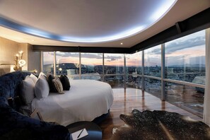 Un dormitorio moderno con una cama grande, vistas a la ciudad y un diseño de techo original.