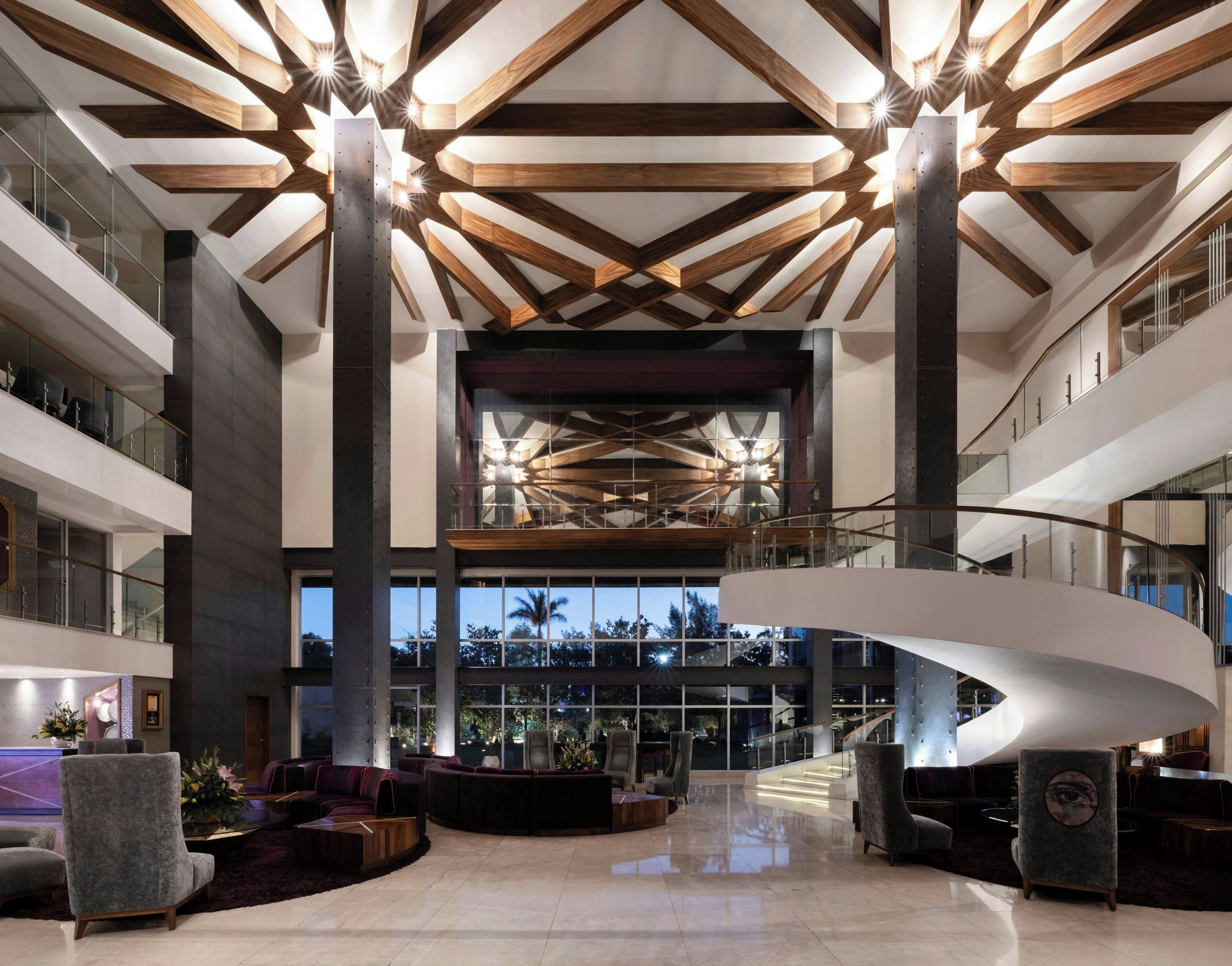 Eine geräumige Lobby mit hoher Decke, modernen Möbeln und einer zentralen Wendeltreppe.