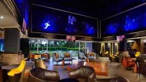 Un espace de détente moderne avec des canapés en cuir, une table basse et un grand écran de télévision diffusant un concert.