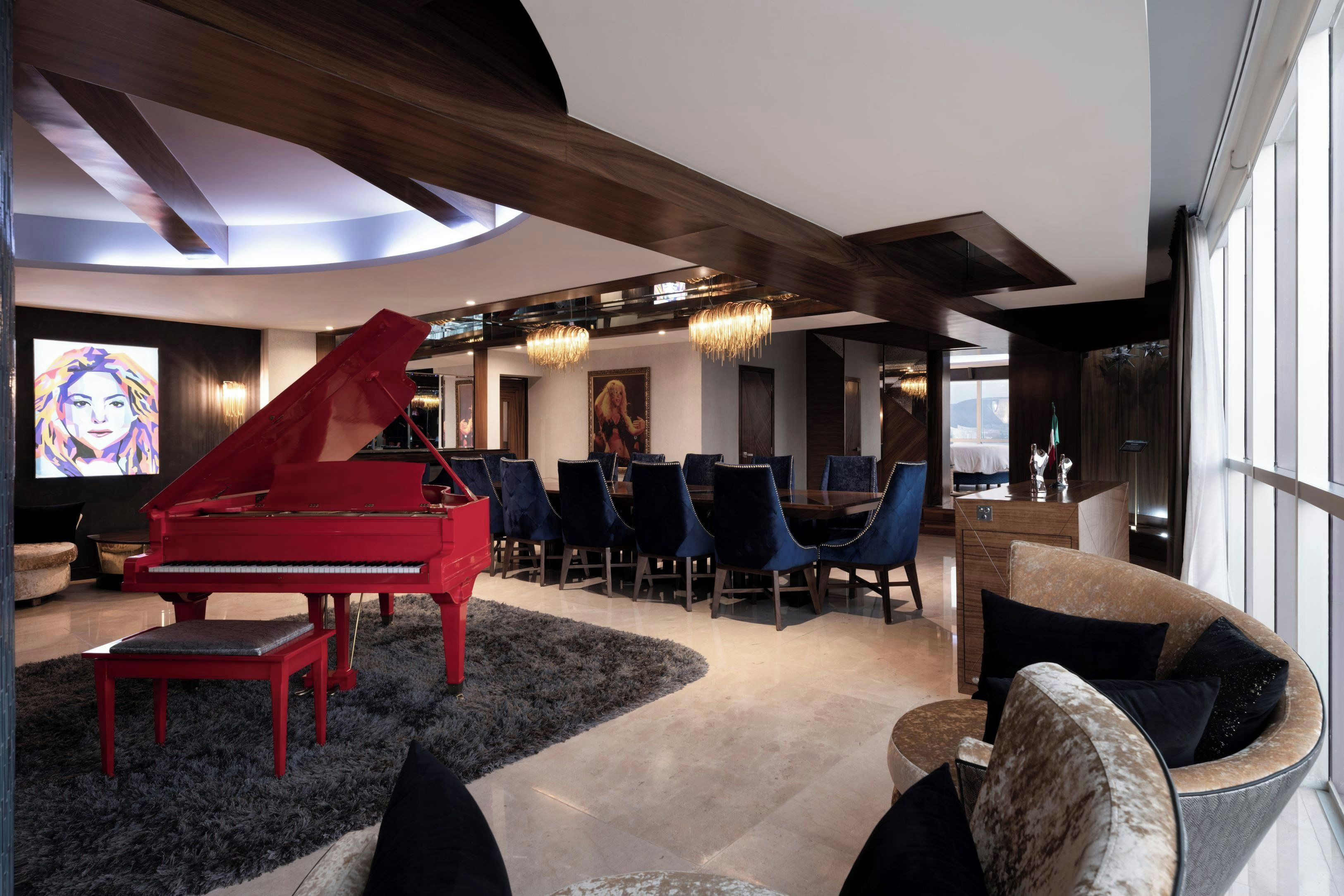 Een ruime woonruimte met een vleugelpiano, comfortabele zithoek en een moderne kroonluchter.