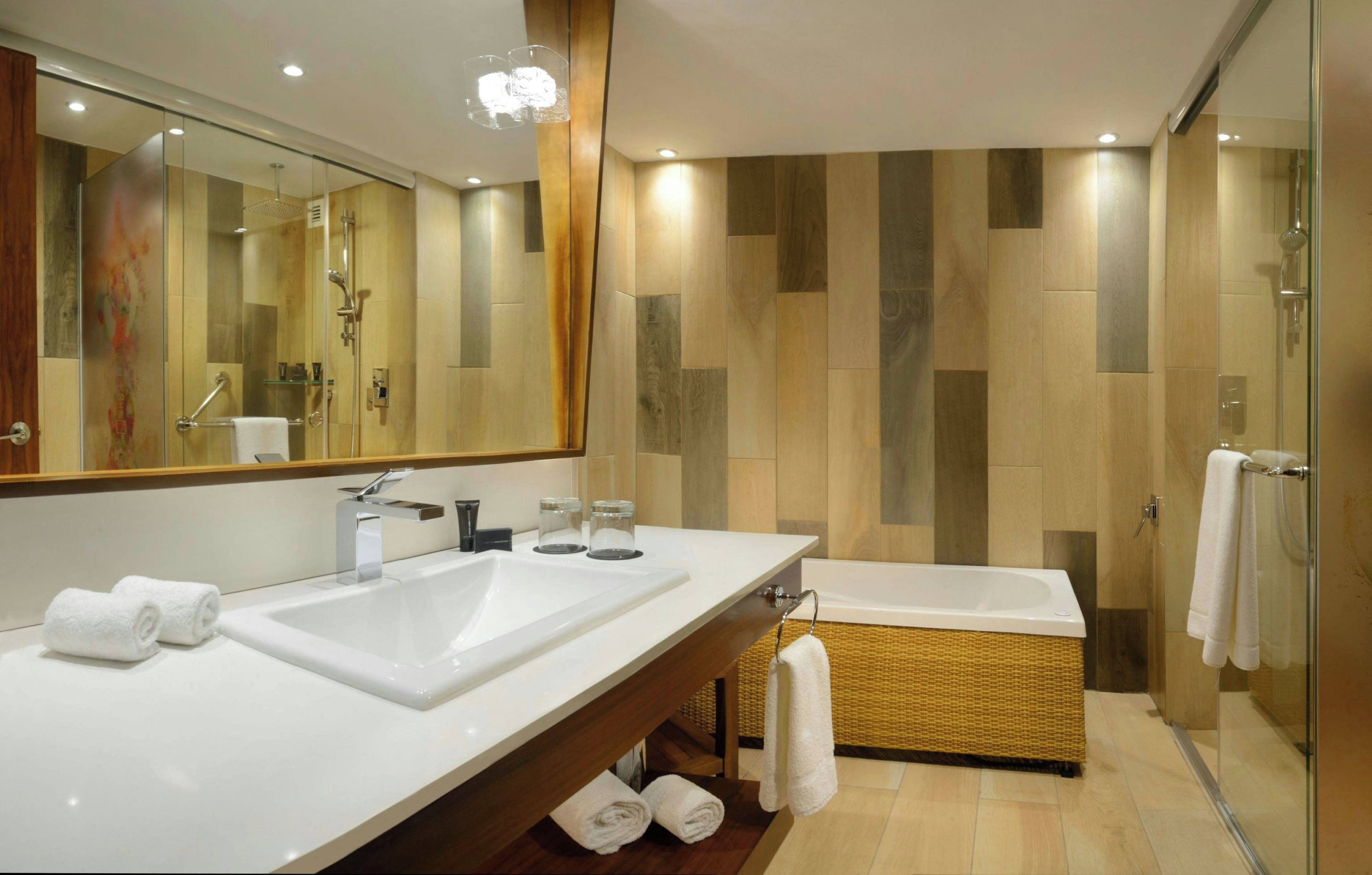 Uma casa de banho moderna com duas pias, um espelho grande, chuveiro e banheira.