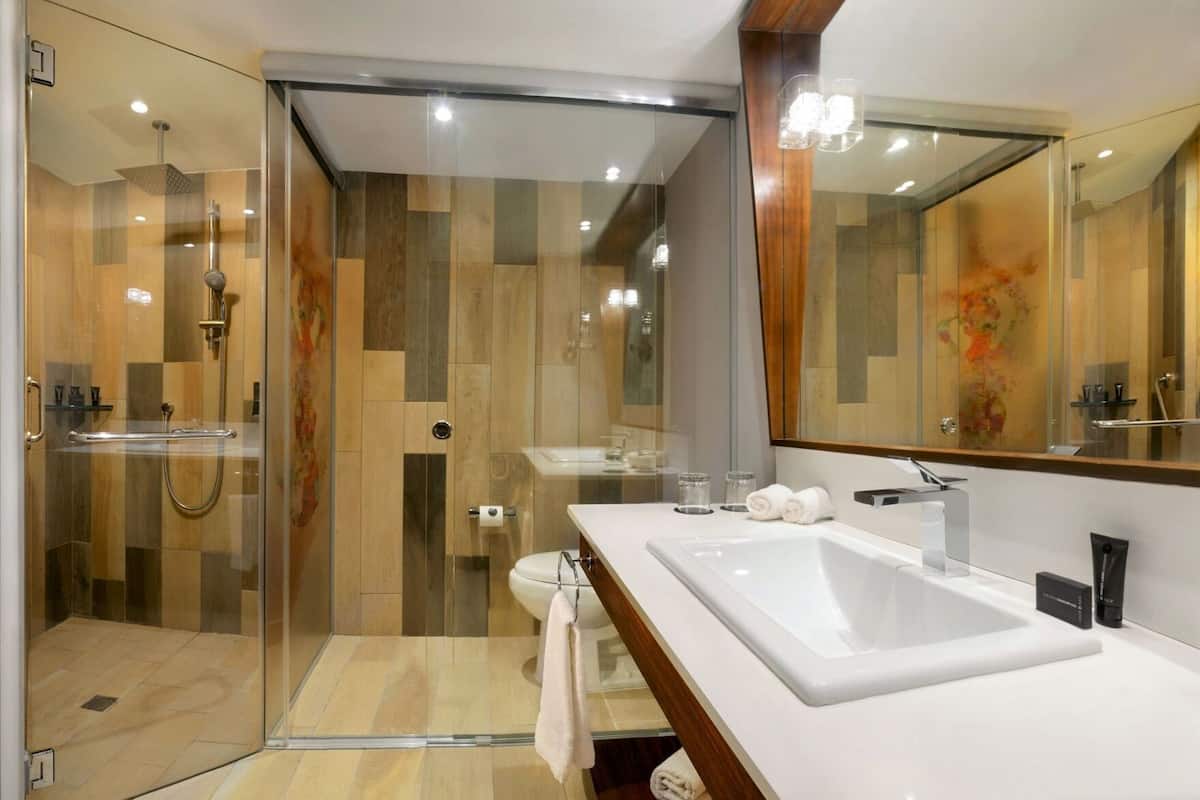 Ein modernes Badezimmer mit einer gläsernen Duschkabine, einem weißen Waschbecken und einem großen Spiegel.