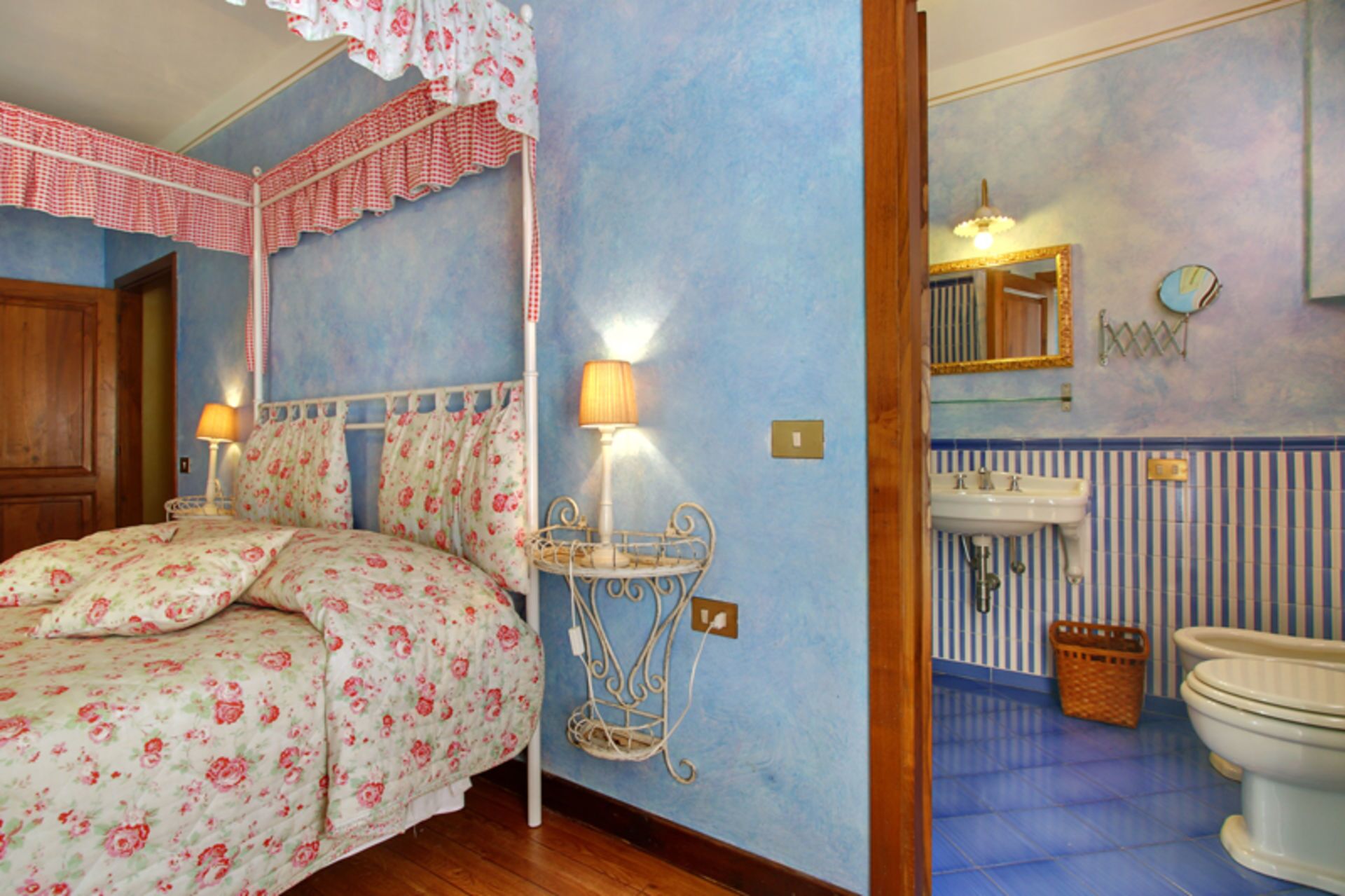 Een slaapkamer met een bloemenbedekking, een bedlampje en een nachtkastje.