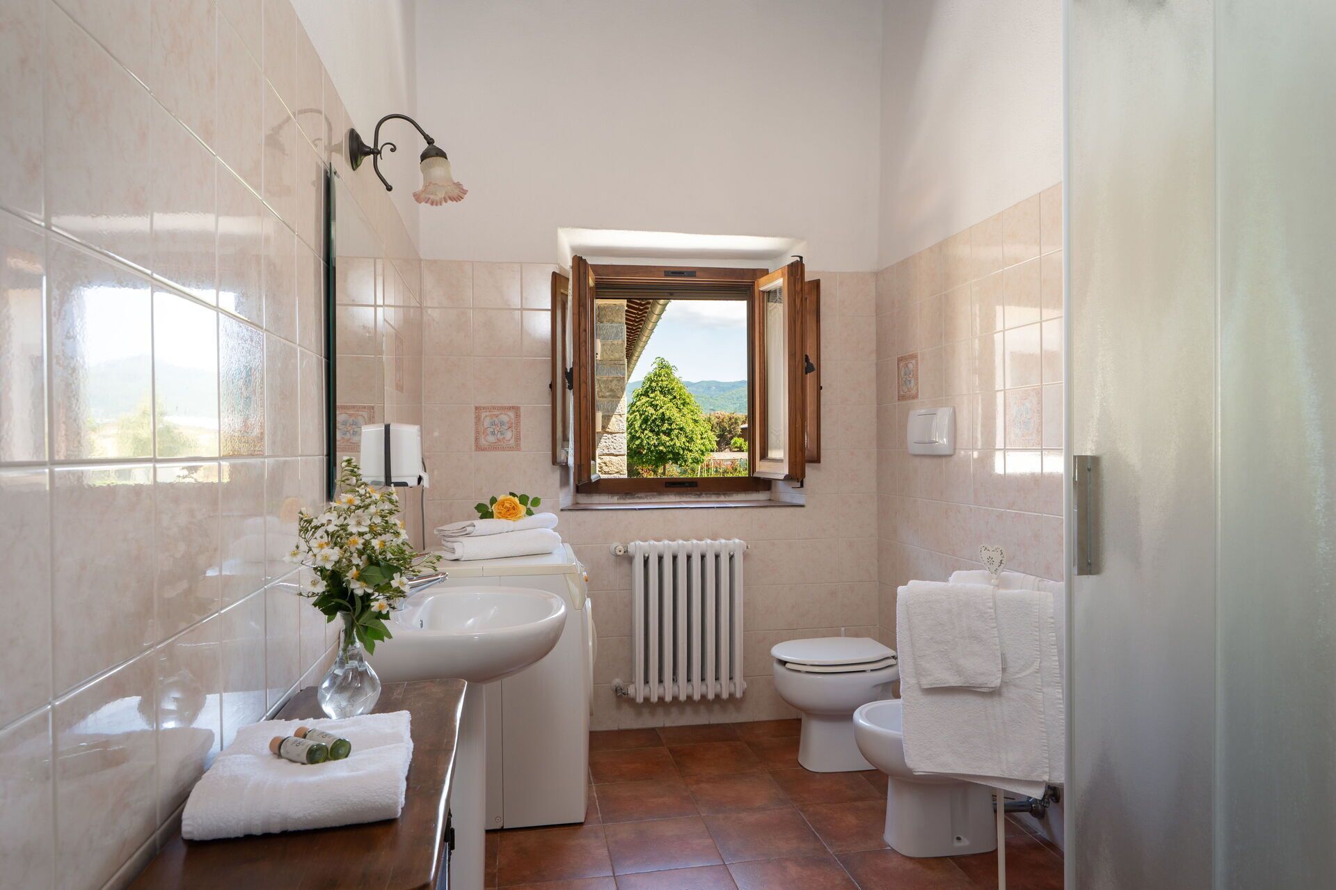 Un baño con ventana, lavabo, inodoro y radiador.