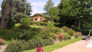 A hillside house with a garden and patio area. - Wonderful private villa for 16 people with private pool, WIFI, TV, patio and panoramic view (Vicchio)