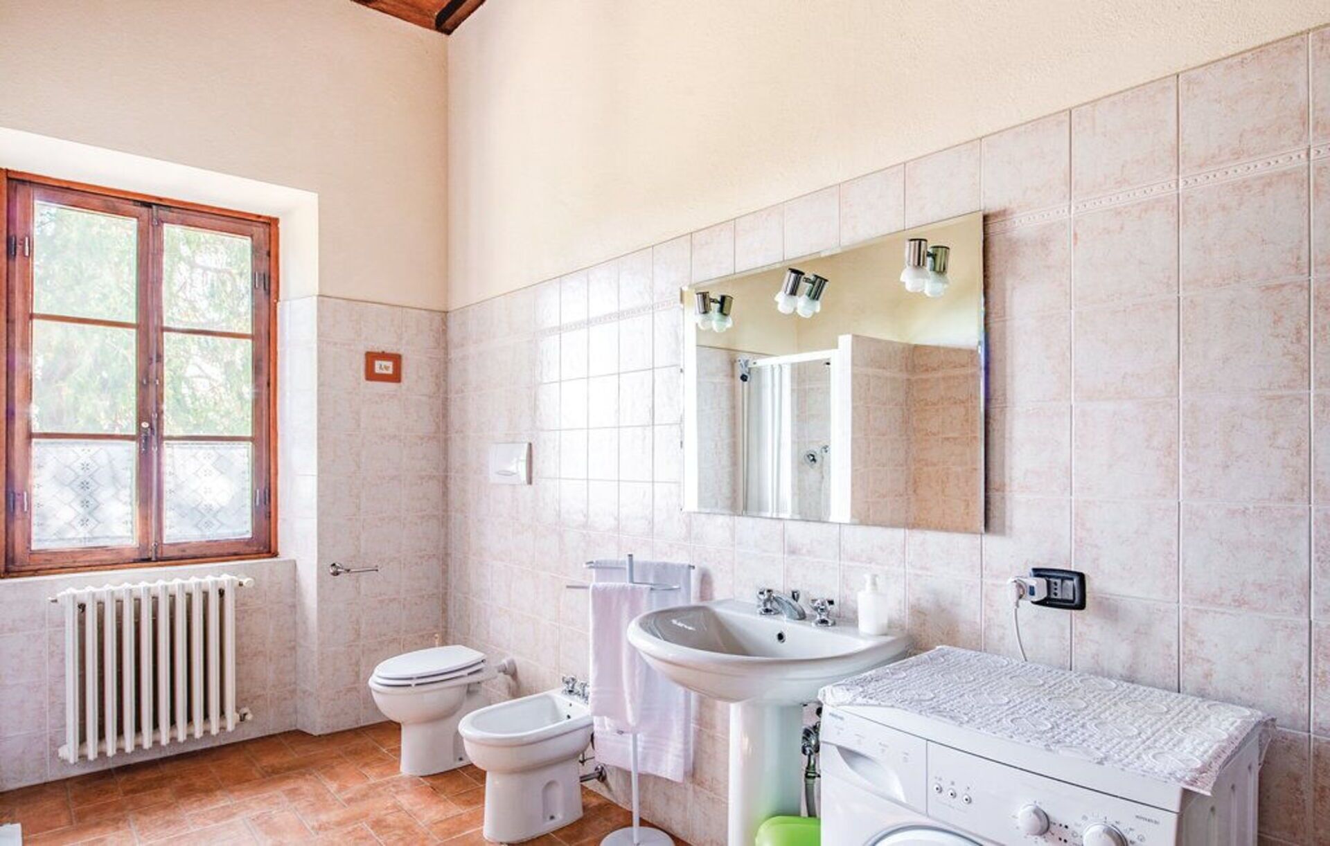 A bathroom with a toilet, bidet, sink, and a mirror.