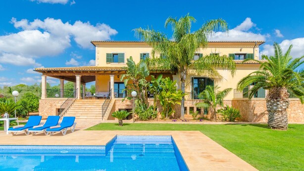 A two-story house with a swimming pool, blue lounge chairs, and palm trees. - CAN BOU -  Villa with private pool only 4 km from the beach on the outskirts of Ses saline (Ses Salines)