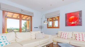 A living room with two beige sofas, a wooden coffee table, and a large window with a view of the outdoors. - CAN BOU -  Villa with private pool only 4 km from the beach on the outskirts of Ses saline (Ses Salines)