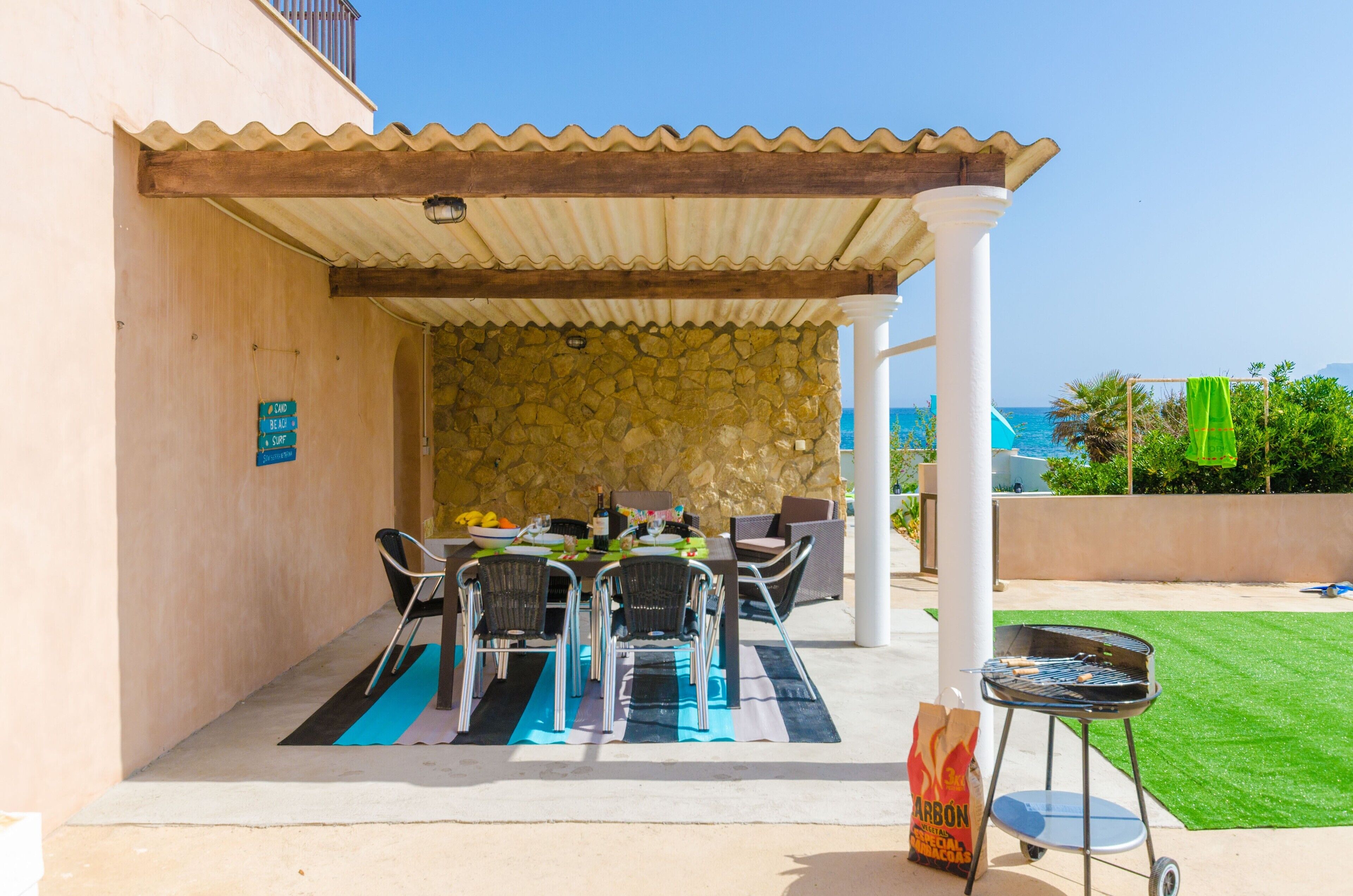 Une terrasse extérieure avec un mur en pierre, un espace salon abrité et un barbecue.